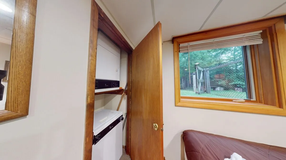 An interior shot focused on a practical laundry area, featuring a washer and dryer next to a window and a door. The window looks out onto the yard, suggesting a connection between indoor and outdoor spaces. The door hints at easy access to the fenced yard, reinforcing the idea of seamless transitions for both guests and their pets.